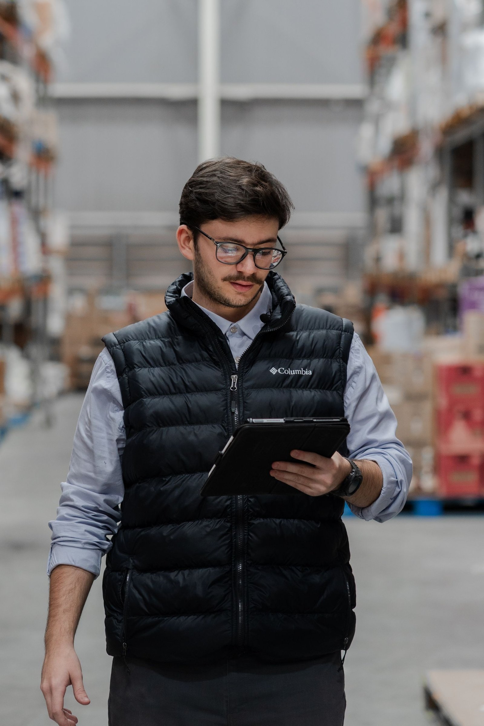 Warehouse worker reviewing inventory data on a tablet between storage racks